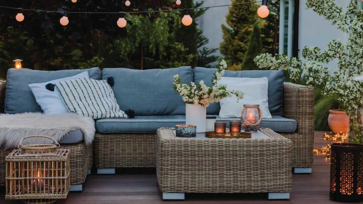 Cozy outdoor seating area with wicker furniture, decorative items, and warm string lights creating a serene evening ambiance.