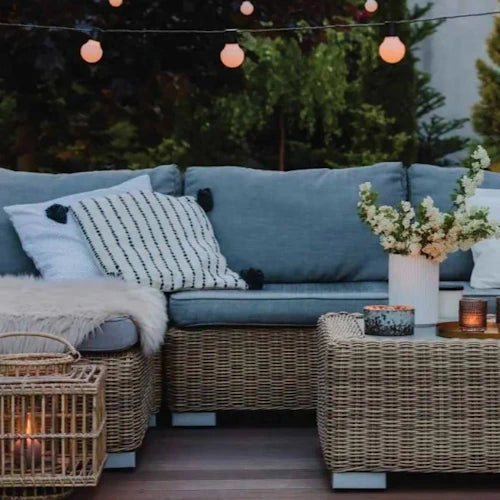 Cozy outdoor seating area with wicker furniture, decorative items, and warm string lights creating a serene evening ambiance.